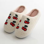 Pair of cream-colored slippers with cherry designs on a white background